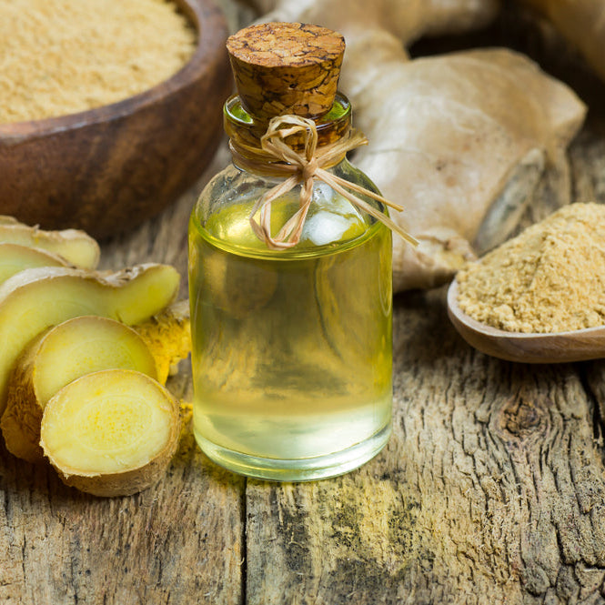 Glass bottle of essential ginger oil, ginger root and powder on wooden rustic background