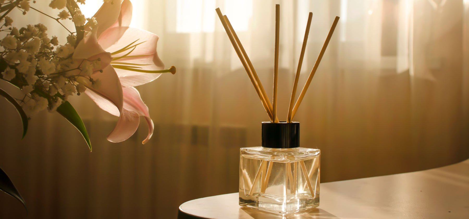 essential oil diffuser on table with flowers and curtain