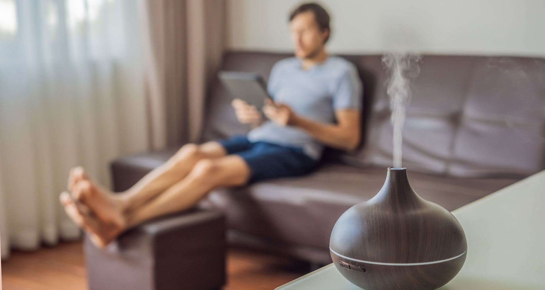 man relaxing in living room with essential oil blend diffusing