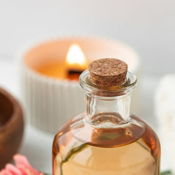 essential oil by scented candles on white table