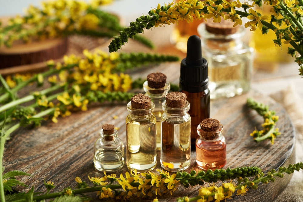 gcms tested essential oil bottles on a wooden table surrounded by herbs and flowers