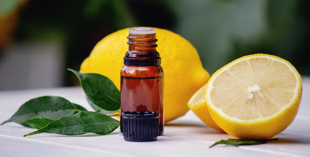 lemon essential oil bottle by cut lemons on table outside