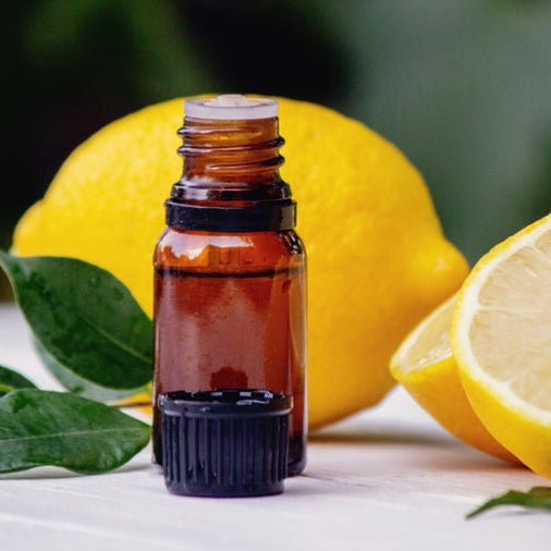 lemon essential oil bottle by cut lemons on table outside