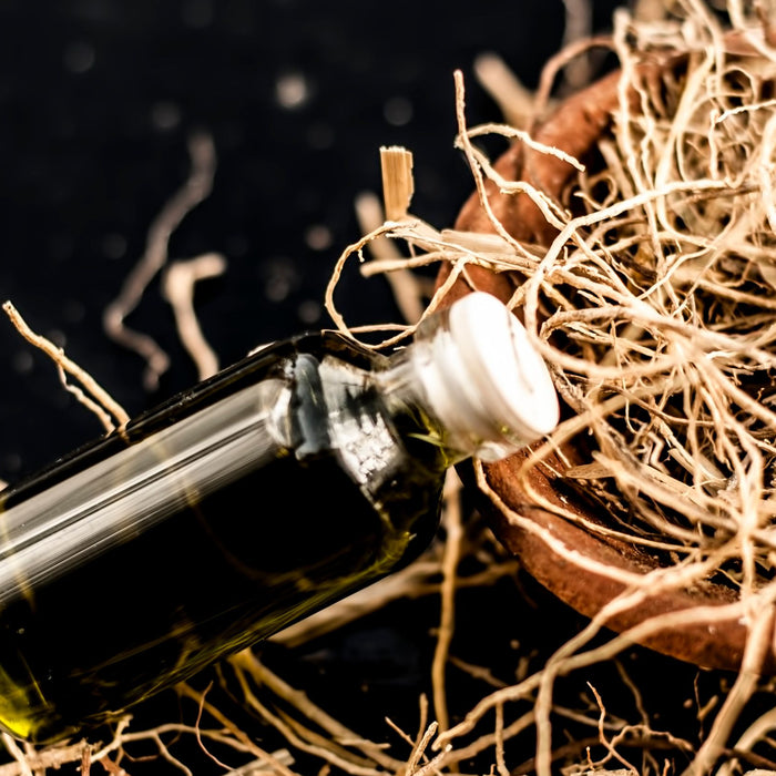 bottle of vetiver essential oil on pile of dried vetiver