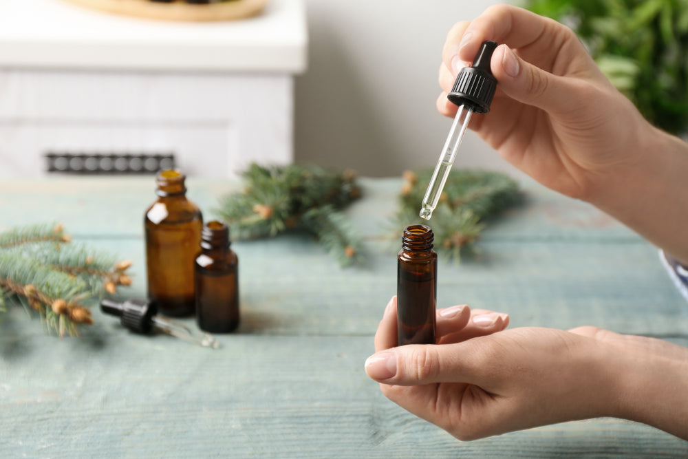 woman using dropper to make essential oil blends in bottle