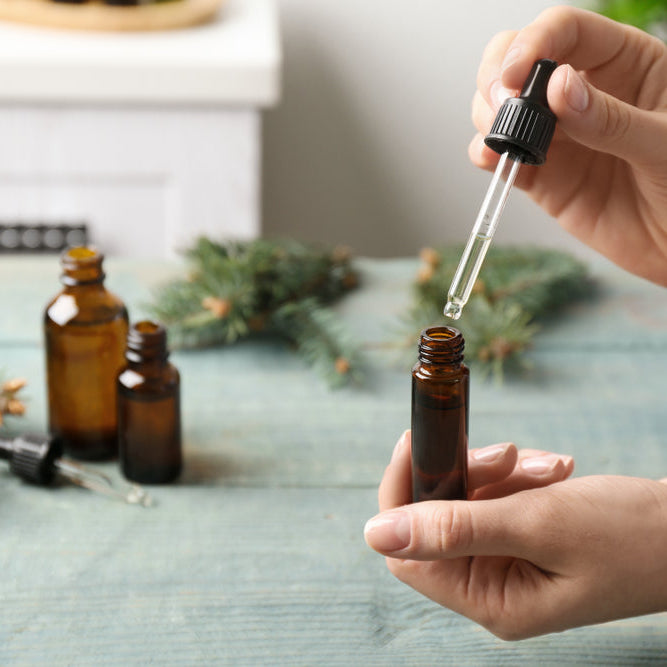 woman using dropper to make essential oil blends in bottle