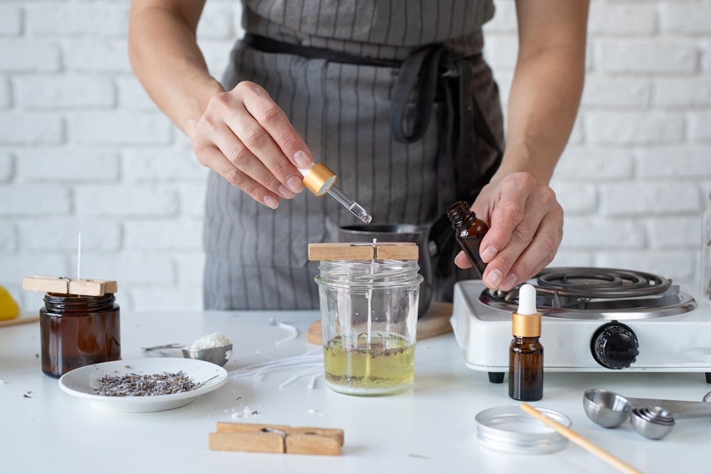 woman with apron adding essential oil to a candle she is making