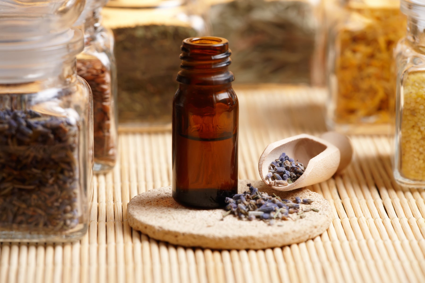 Jars of dried plants with a scoop of lavender to make a patchouli and lavender blend.