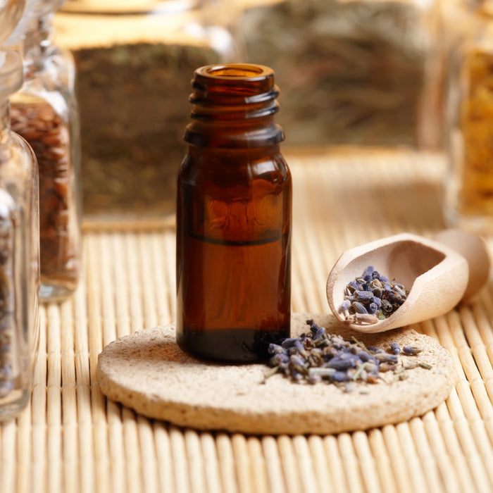 Jars of dried plants with a scoop of lavender to make a patchouli and lavender blend.
