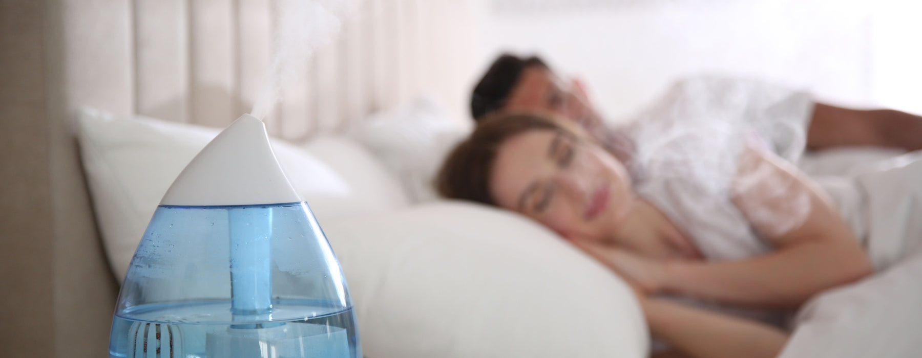man and woman in bed sleeping by diffuser with essential oil blend for sleep
