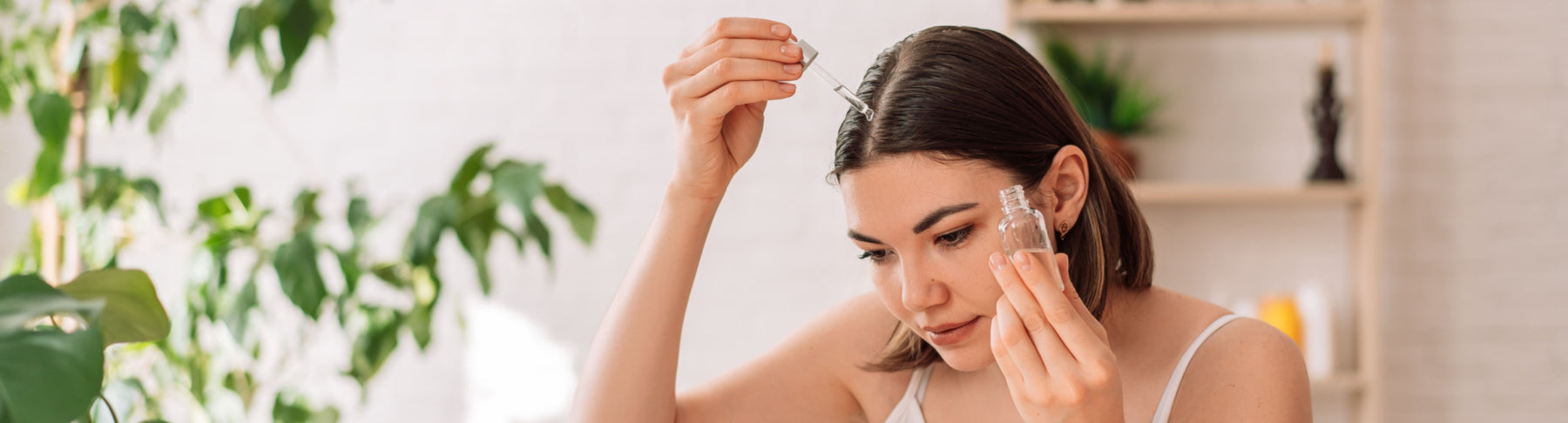 woman applying essential oil to hair