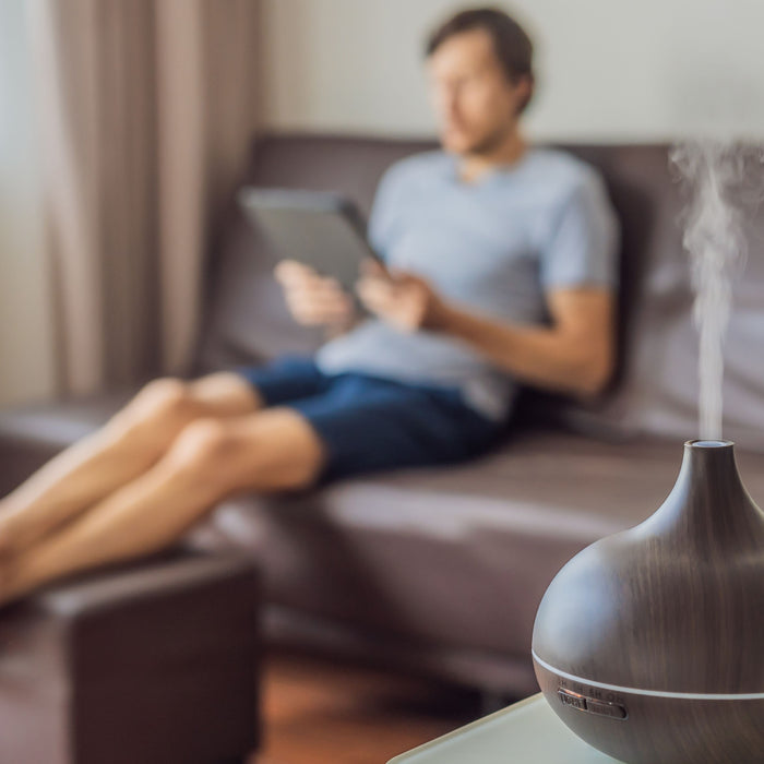 man relaxing in living room with essential oil blend diffusing